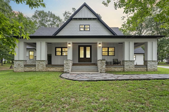 back house at dusk featuring a yard and covered porch