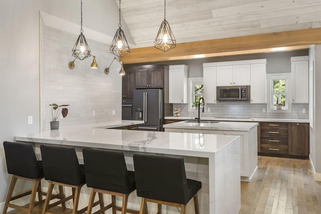 kitchen featuring white cabinets, sink, backsplash, appliances with stainless steel finishes, and light hardwood / wood-style floors