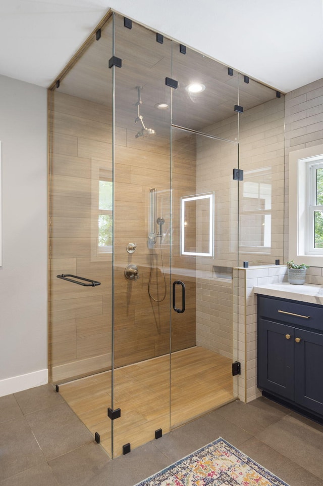 bathroom featuring an enclosed shower, vanity, and tile walls