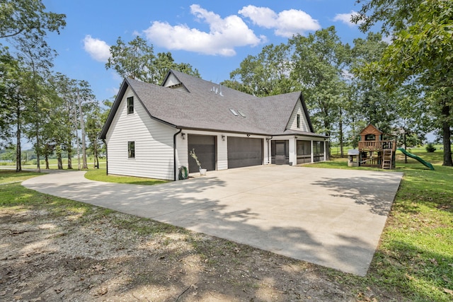 view of side of home featuring a playground, a garage, and a lawn