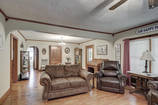 living room with a textured ceiling, light wood-type flooring, a notable chandelier, and a healthy amount of sunlight