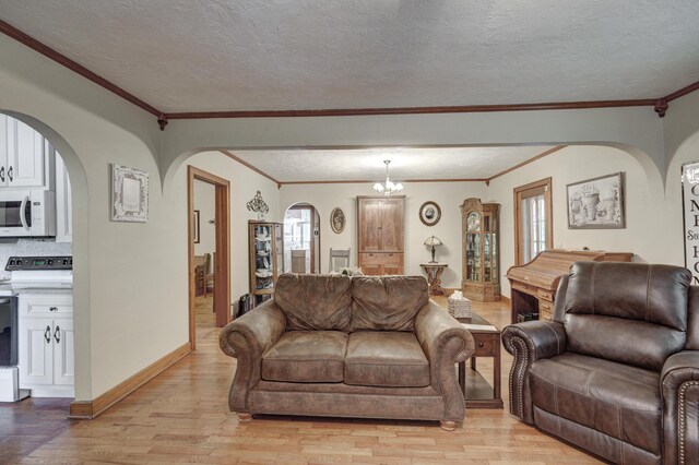 living room featuring a textured ceiling, a chandelier, ornamental molding, and light hardwood / wood-style flooring