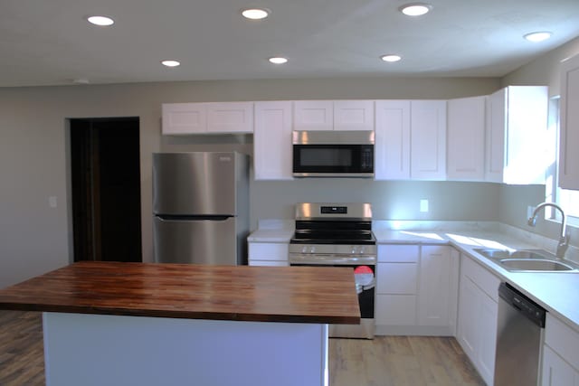 410 Park St, Taneyville, MO 65759 - kitchen with appliances with stainless steel finishes, butcher block countertops, a sink, light wood-type flooring, and a center island