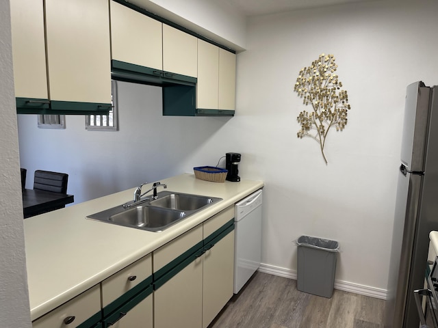 kitchen with stainless steel refrigerator, hardwood / wood-style floors, sink, and white dishwasher