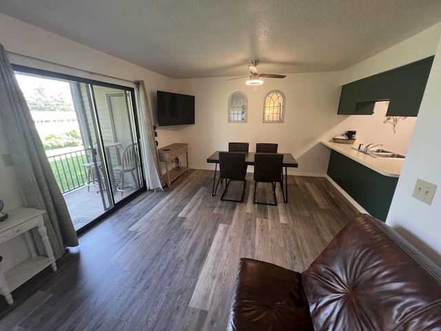 dining room with ceiling fan, dark wood-type flooring, sink, and a textured ceiling