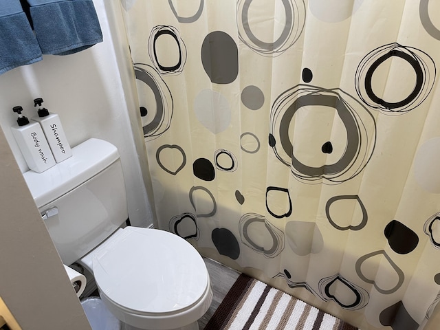 bathroom featuring toilet and curtained shower