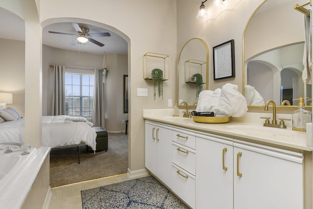 bathroom featuring tile patterned floors, ceiling fan, vanity, and tiled bath