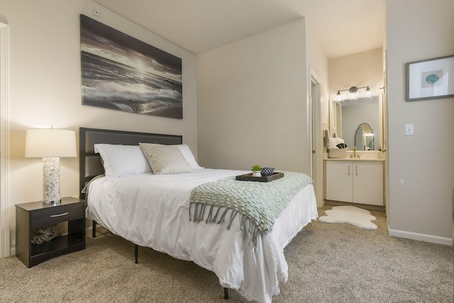 carpeted bedroom featuring sink and ensuite bath