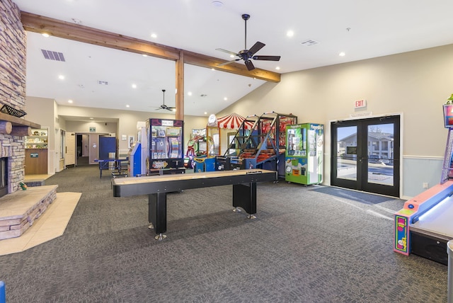 recreation room featuring ceiling fan, beam ceiling, a stone fireplace, high vaulted ceiling, and carpet floors