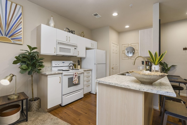 kitchen with sink, white appliances, white cabinetry, dark hardwood / wood-style floors, and light stone countertops