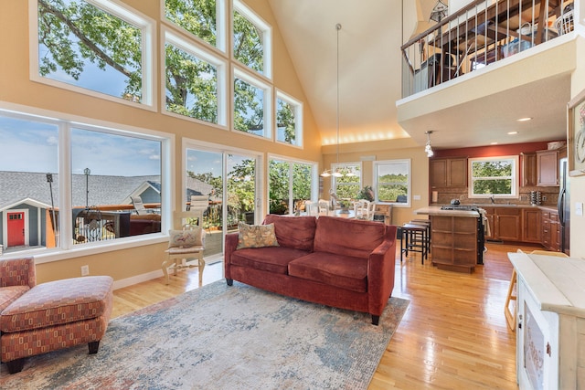 living room featuring light wood-type flooring, a towering ceiling, and sink