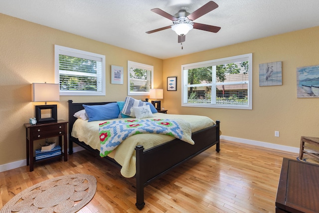 bedroom featuring ceiling fan, hardwood / wood-style floors, and a textured ceiling