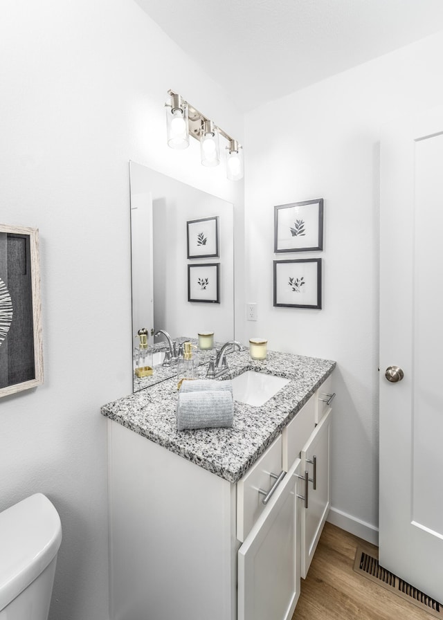 bathroom featuring vanity, toilet, and hardwood / wood-style flooring