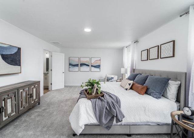 bedroom with ensuite bathroom and carpet