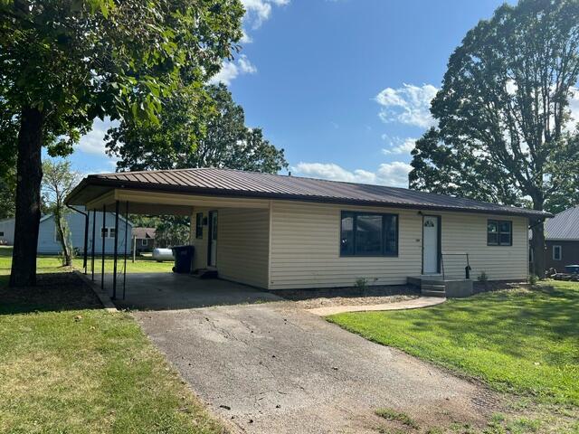 ranch-style home featuring a carport and a front yard