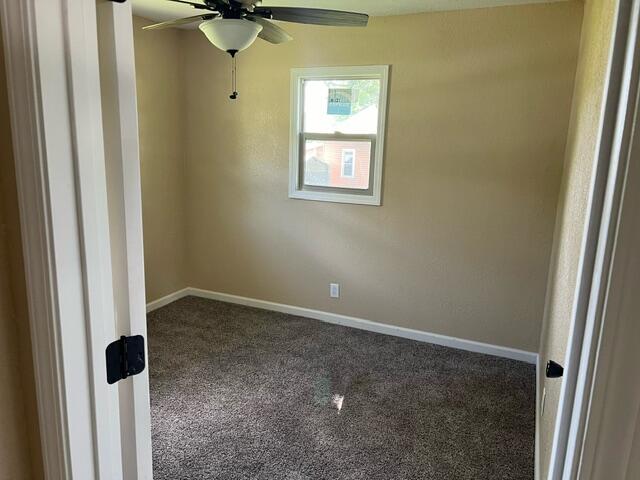 carpeted spare room featuring ceiling fan