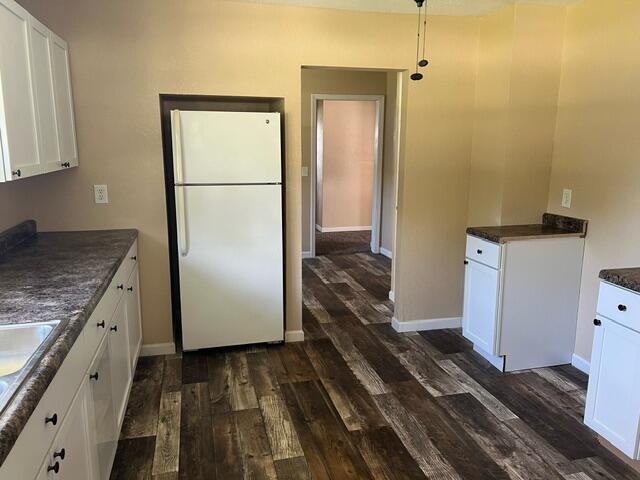 106 Martin St, Licking, MO 65542 - kitchen featuring dark countertops, white cabinets, baseboards, dark wood-type flooring, and freestanding refrigerator