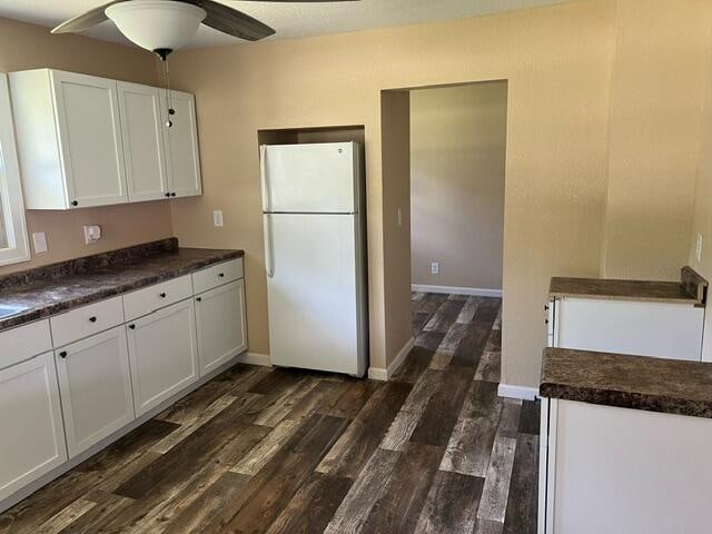 kitchen featuring white refrigerator, ceiling fan, dark wood-type flooring, and white cabinetry