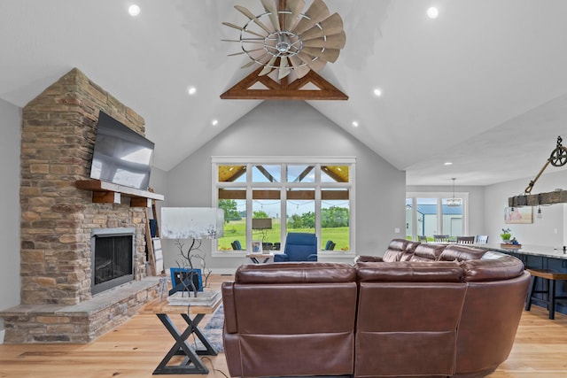 living room with a fireplace, light hardwood / wood-style floors, high vaulted ceiling, and a healthy amount of sunlight