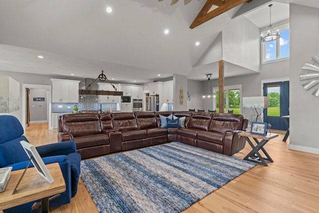 living room with high vaulted ceiling, a chandelier, and light hardwood / wood-style flooring