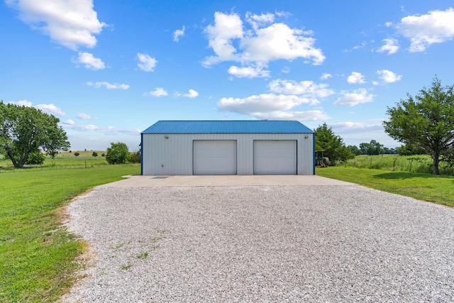 garage with a rural view and a yard