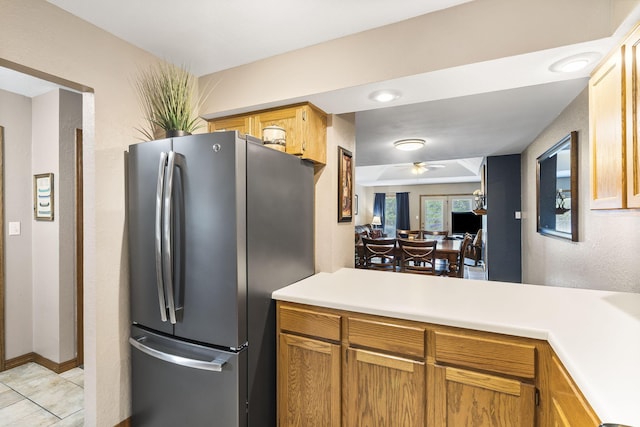 kitchen with light tile patterned floors, light countertops, freestanding refrigerator, and ceiling fan
