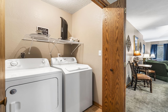 laundry area with washing machine and clothes dryer, a textured wall, light carpet, and laundry area