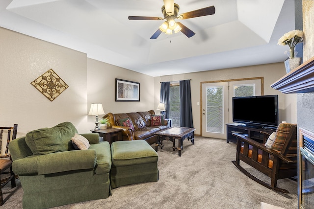 living room featuring ceiling fan, a tray ceiling, and light carpet