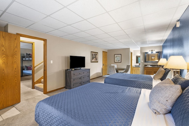 bedroom with a paneled ceiling, baseboards, and light carpet