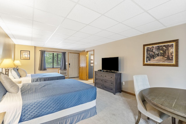 bedroom with baseboards, a paneled ceiling, and light colored carpet