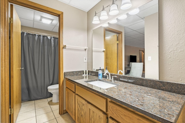 bathroom featuring vanity, toilet, a drop ceiling, tile patterned flooring, and a shower with shower curtain