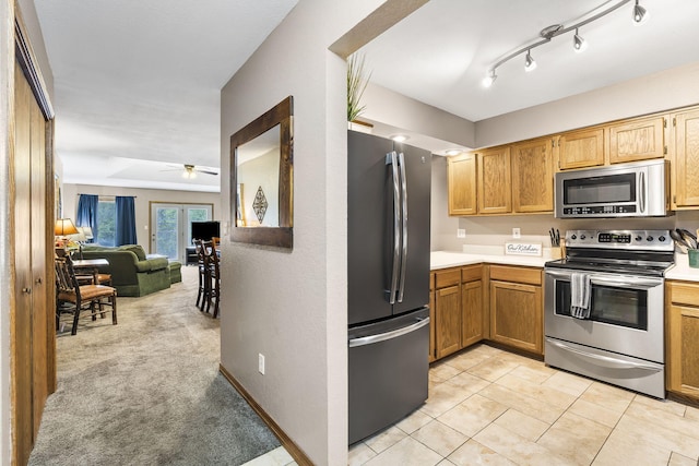 kitchen with ceiling fan, open floor plan, stainless steel appliances, and light countertops
