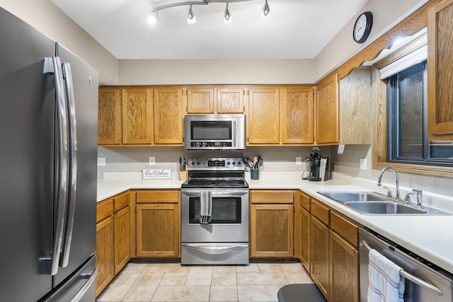 kitchen featuring brown cabinetry, stainless steel appliances, light countertops, and a sink