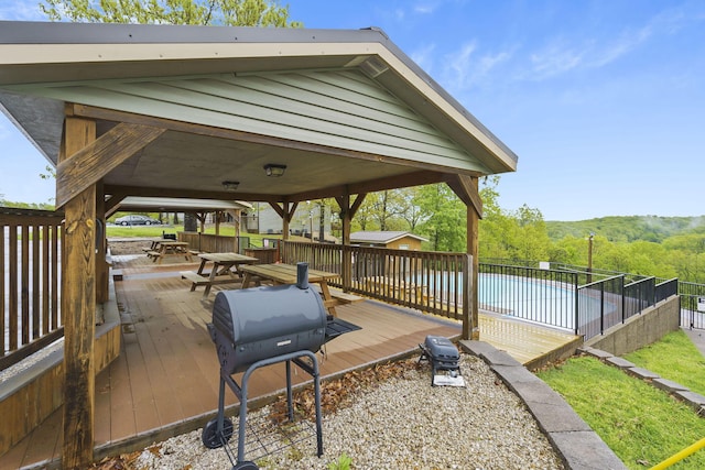 wooden terrace with a pool, a gazebo, fence, and a grill