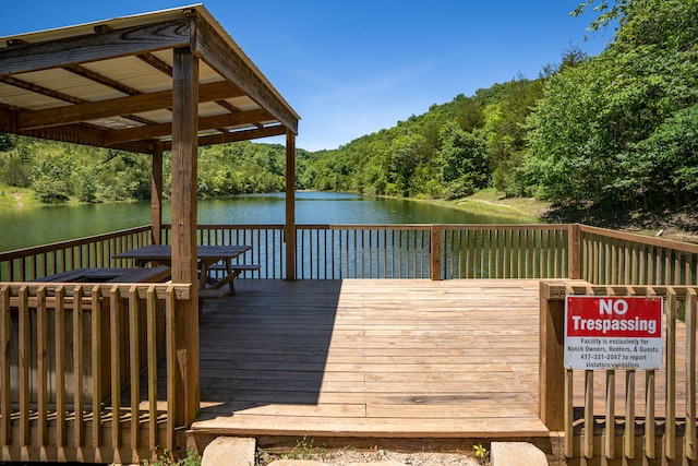 dock area featuring a deck with water view and a view of trees