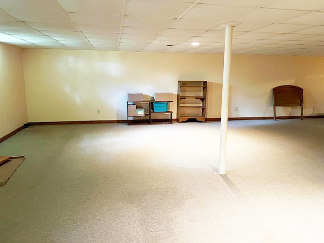 basement featuring a paneled ceiling and carpet