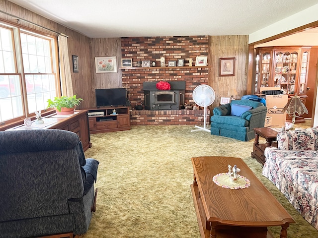 carpeted living room featuring a textured ceiling, wooden walls, and a wood stove