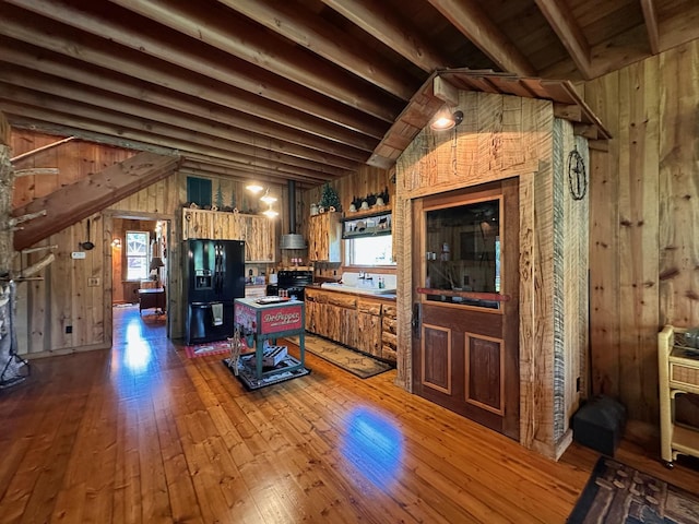 kitchen featuring wood walls, hardwood / wood-style floors, black fridge with ice dispenser, and a wealth of natural light