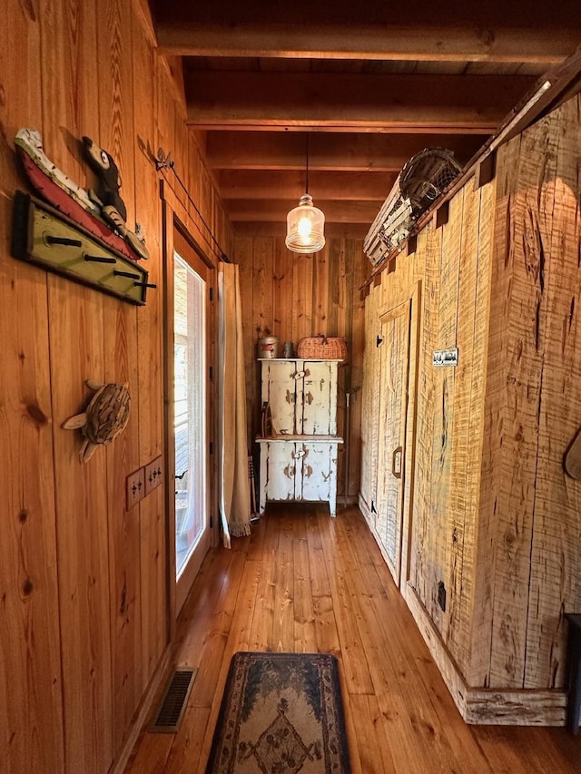 interior space with beamed ceiling, hardwood / wood-style flooring, and wooden walls