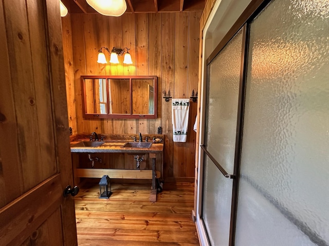 bathroom featuring wood-type flooring, wooden walls, and a shower with shower door