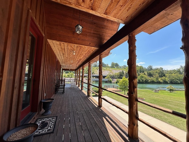 wooden terrace with a yard and a water view