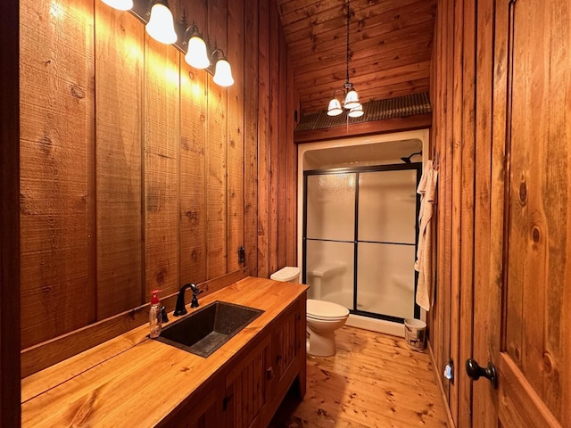 bathroom with hardwood / wood-style floors, vanity, walk in shower, wood walls, and toilet