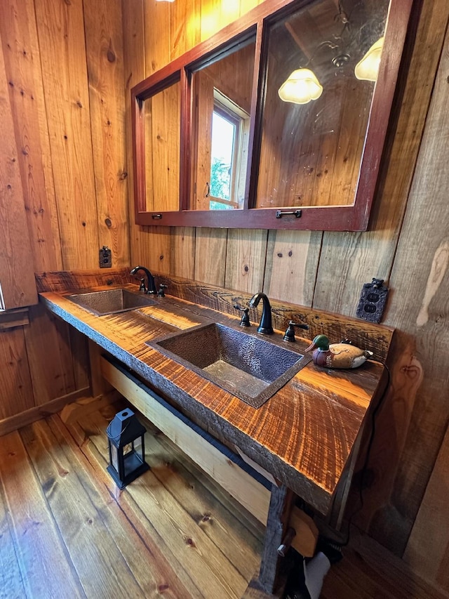 kitchen with hardwood / wood-style flooring, wood walls, and sink