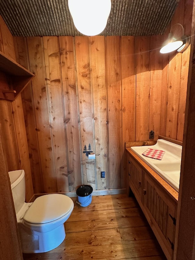 bathroom with hardwood / wood-style flooring, wooden walls, and toilet