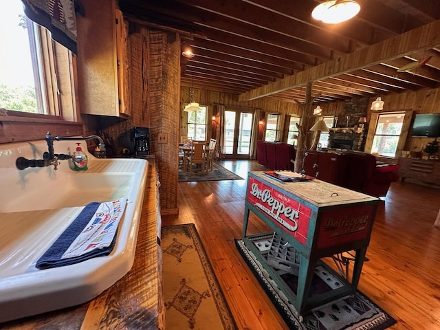 kitchen with wooden walls, dark hardwood / wood-style floors, beam ceiling, and a fireplace