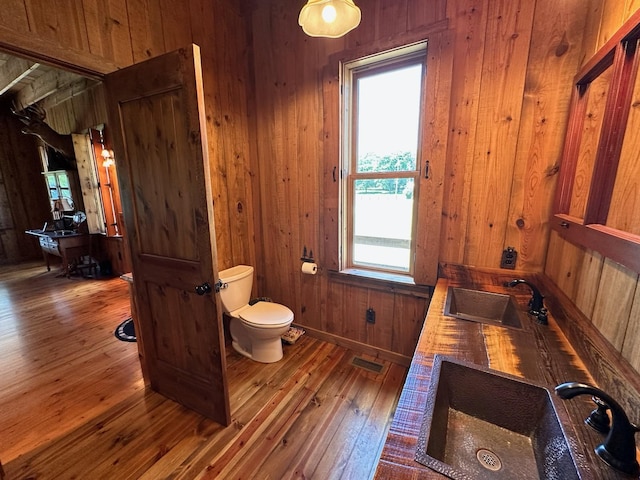 bathroom featuring sink, wood walls, toilet, and wood-type flooring