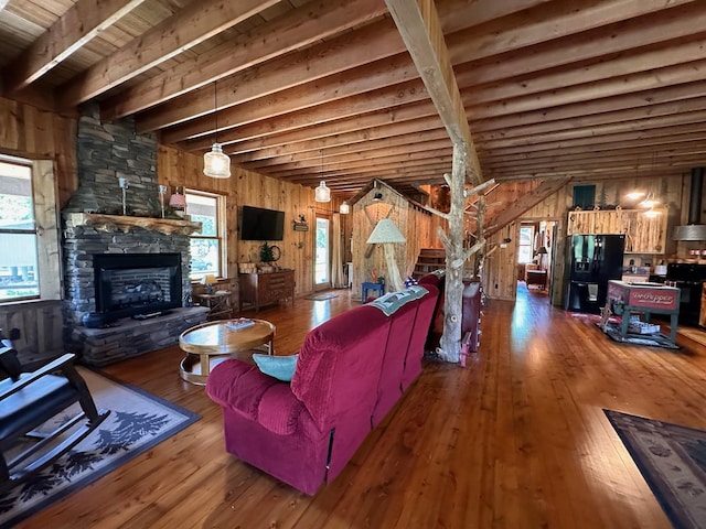 living room featuring plenty of natural light, hardwood / wood-style floors, wooden walls, and a stone fireplace