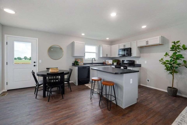 kitchen featuring white cabinets, sink, dark wood-type flooring, black appliances, and a kitchen bar