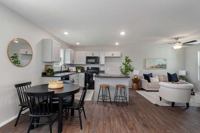 dining room featuring dark wood-type flooring, sink, and ceiling fan