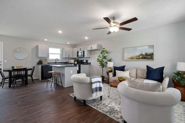 living room featuring ceiling fan, dark wood-type flooring, and sink